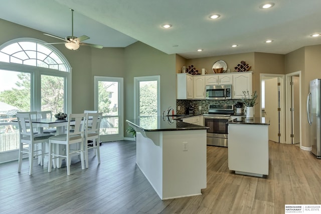 kitchen featuring appliances with stainless steel finishes, a peninsula, a ceiling fan, white cabinetry, and light wood-type flooring