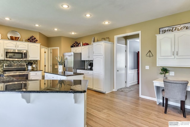kitchen featuring light wood-style floors, white cabinetry, appliances with stainless steel finishes, and tasteful backsplash