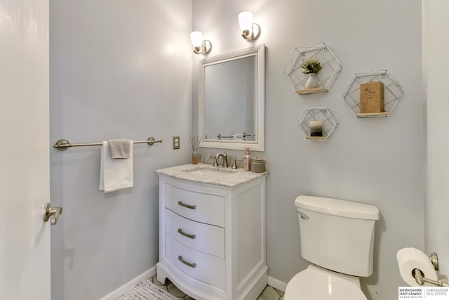 half bathroom with vanity, baseboards, and toilet