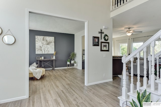 entrance foyer featuring baseboards, ceiling fan, light wood-style flooring, and stairway