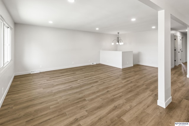 unfurnished living room with visible vents, wood finished floors, baseboards, recessed lighting, and a notable chandelier