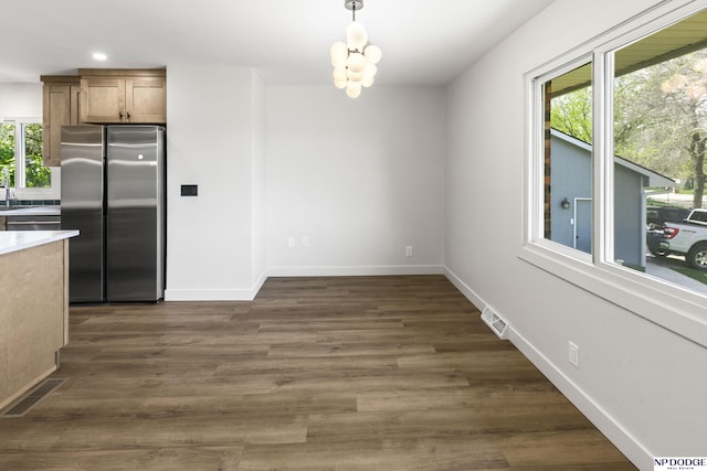 unfurnished dining area with a notable chandelier, dark wood finished floors, recessed lighting, baseboards, and visible vents