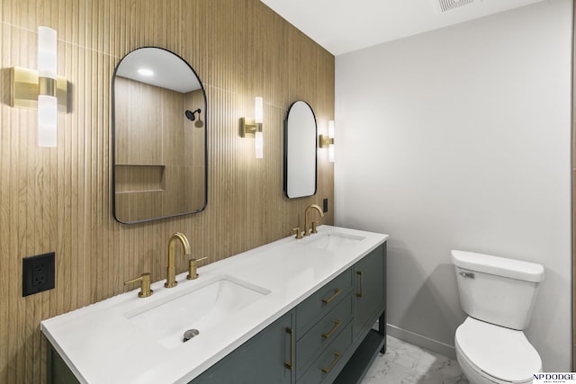 bathroom featuring a sink, toilet, double vanity, and marble finish floor