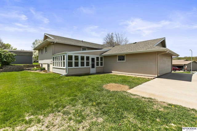 rear view of house with a lawn, a shingled roof, and a sunroom