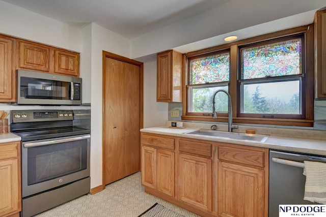 kitchen with light countertops, stainless steel appliances, brown cabinets, and a sink