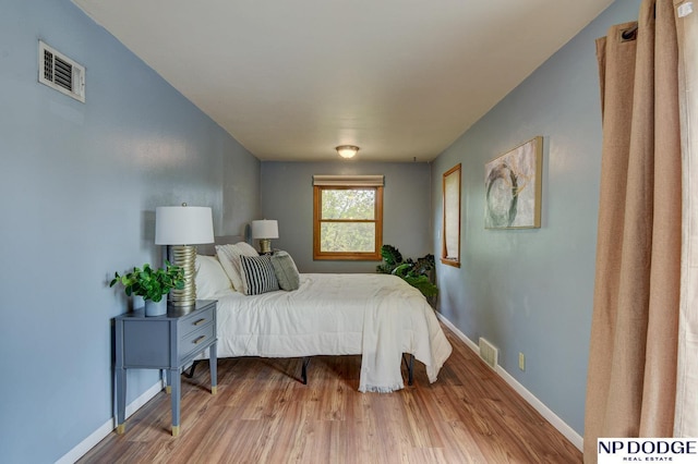 bedroom featuring baseboards, visible vents, and wood finished floors
