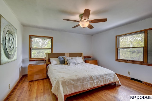 bedroom featuring baseboards, multiple windows, and light wood finished floors