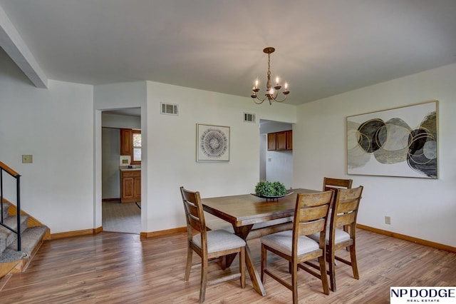 dining room featuring visible vents, light wood-style flooring, stairs, and a notable chandelier