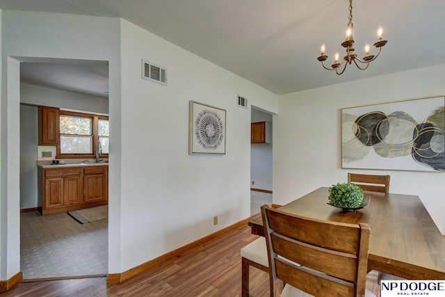 dining area with baseboards, a notable chandelier, visible vents, and wood finished floors