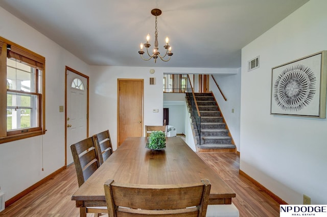 dining room featuring visible vents, stairs, wood finished floors, baseboards, and a chandelier