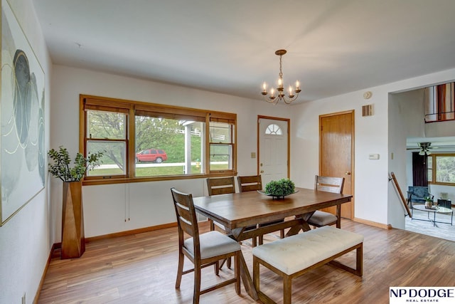 dining area featuring baseboards, light wood finished floors, a chandelier, and visible vents