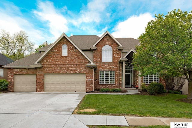 traditional home featuring a shingled roof, a front yard, driveway, and brick siding