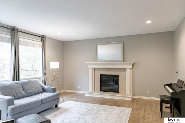 living room with recessed lighting, baseboards, a tiled fireplace, and light wood-type flooring