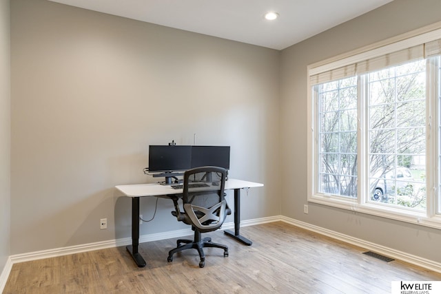 home office with a healthy amount of sunlight, baseboards, wood finished floors, and visible vents