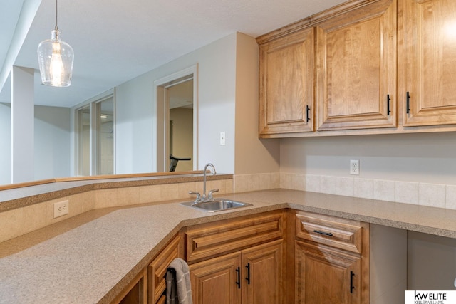 kitchen featuring light countertops, decorative light fixtures, and a sink