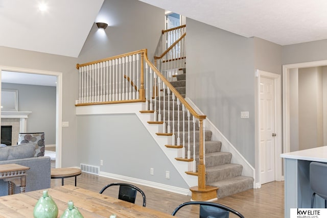 interior space with visible vents, stairs, wood finished floors, a fireplace, and baseboards