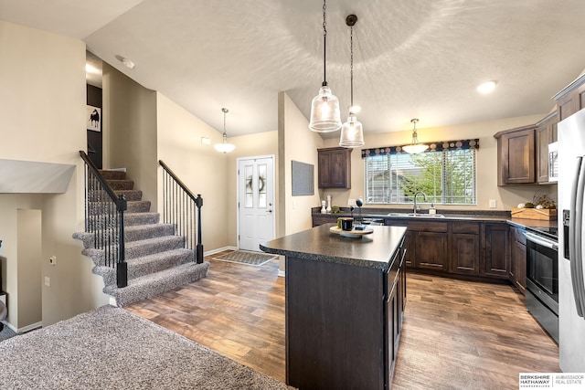 kitchen with electric range, dark countertops, dark brown cabinetry, a center island, and lofted ceiling