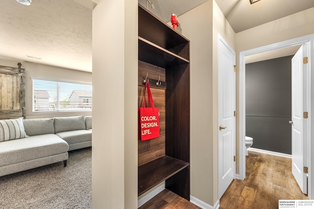 mudroom featuring a textured ceiling, baseboards, and wood finished floors