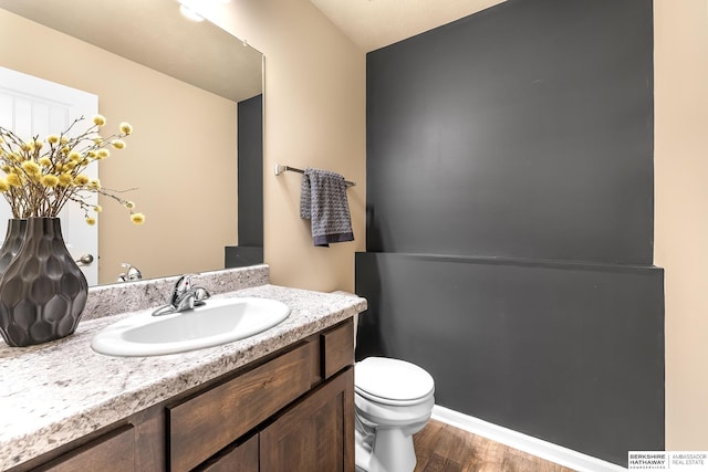 half bath featuring vanity, toilet, and wood finished floors