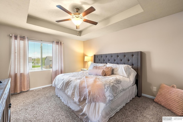 carpeted bedroom with baseboards, ceiling fan, and a tray ceiling
