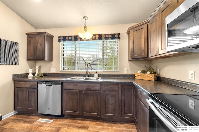 kitchen featuring visible vents, dark countertops, light wood-style floors, a sink, and appliances with stainless steel finishes