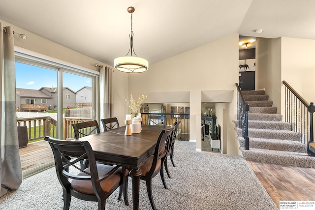 dining area with vaulted ceiling, stairs, and wood finished floors