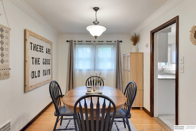 dining room featuring baseboards, visible vents, ornamental molding, and light wood-type flooring