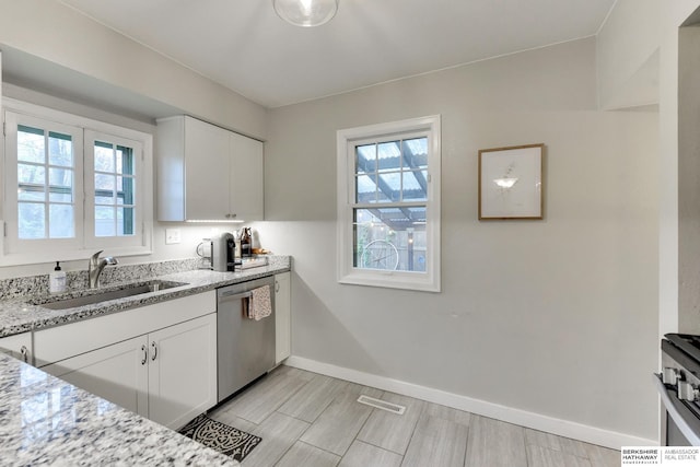 kitchen with a sink, baseboards, white cabinets, and dishwasher