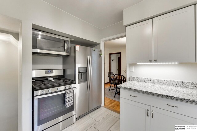 kitchen featuring white cabinetry, light stone countertops, and stainless steel appliances