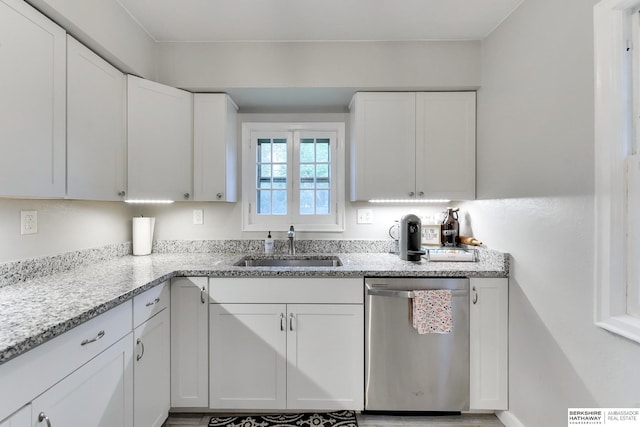 kitchen with a sink, light stone countertops, white cabinetry, and dishwasher