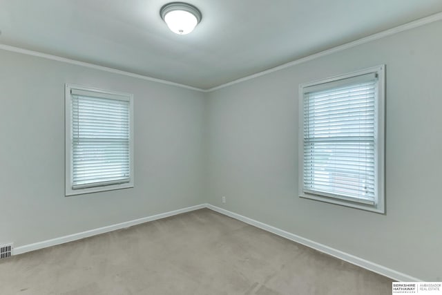 carpeted spare room with baseboards, crown molding, and visible vents