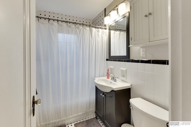 bathroom featuring vanity, curtained shower, toilet, and tile walls