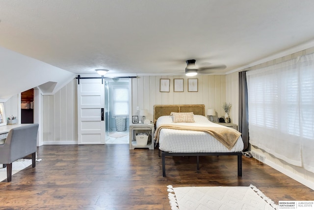 bedroom with a barn door, wood finished floors, and visible vents