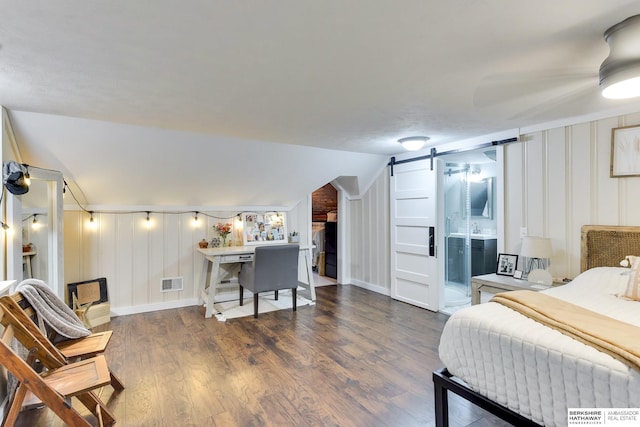 bedroom with visible vents, a barn door, baseboards, and wood finished floors