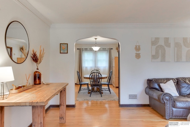 dining room with visible vents, arched walkways, baseboards, light wood-style floors, and ornamental molding