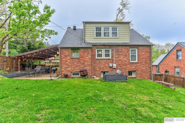 rear view of house with a lawn, a fenced backyard, and brick siding