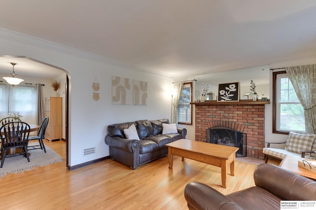 living area featuring visible vents, plenty of natural light, light wood-style flooring, and crown molding