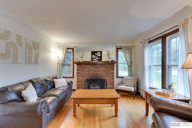 living area with ornamental molding, light wood-style flooring, and a brick fireplace