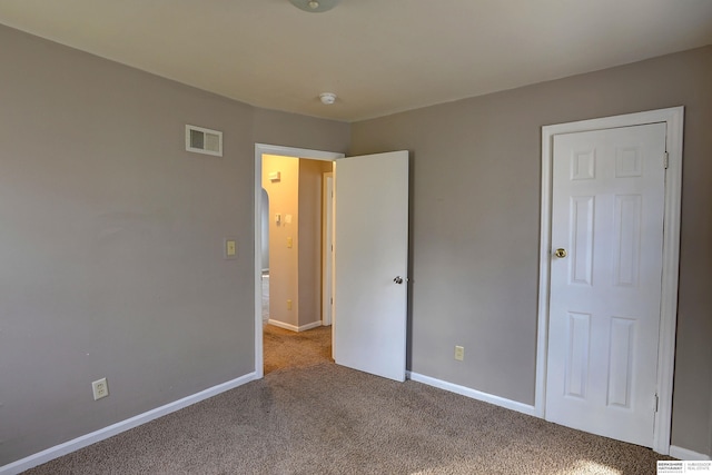 unfurnished bedroom with baseboards, carpet, and visible vents