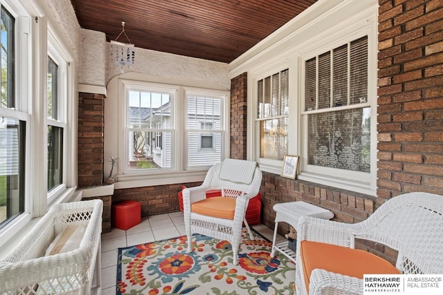 sunroom / solarium with wooden ceiling, tile patterned floors, and brick wall