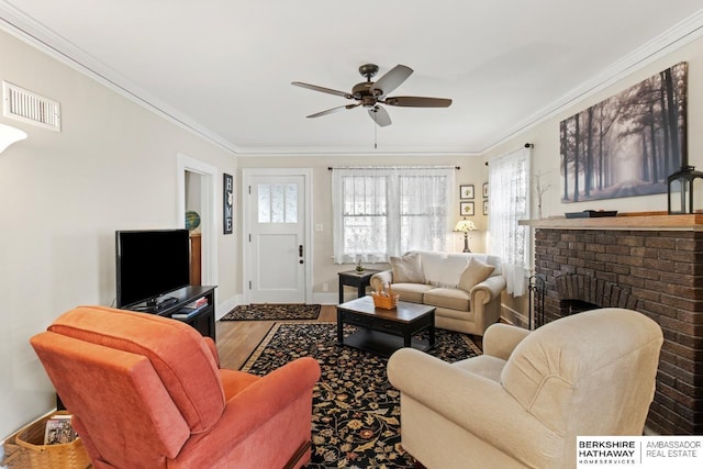 living room with visible vents, crown molding, wood finished floors, baseboards, and ceiling fan