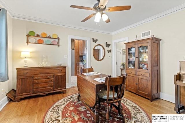 interior space with light wood-style flooring, a ceiling fan, baseboards, visible vents, and ornamental molding