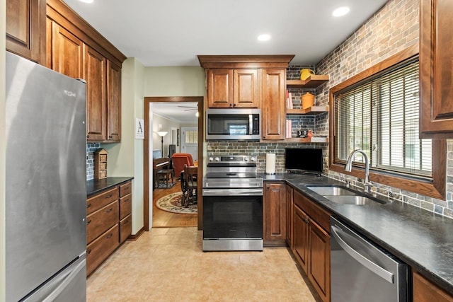 kitchen with dark countertops, brown cabinets, a sink, appliances with stainless steel finishes, and backsplash