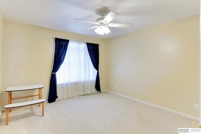 carpeted spare room featuring baseboards, ceiling fan, and visible vents