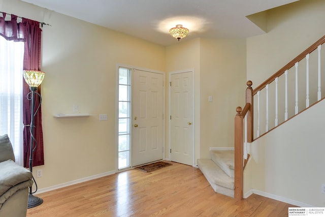 foyer entrance featuring stairway, baseboards, wood finished floors, and visible vents