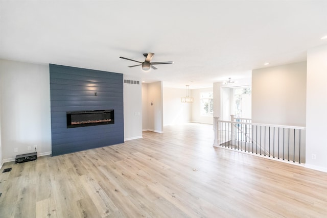 unfurnished living room with ceiling fan, visible vents, a large fireplace, wood finished floors, and baseboards