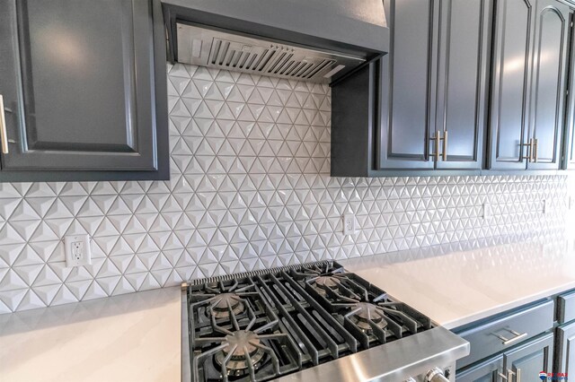 kitchen with light countertops, gray cabinets, cooktop, tasteful backsplash, and under cabinet range hood