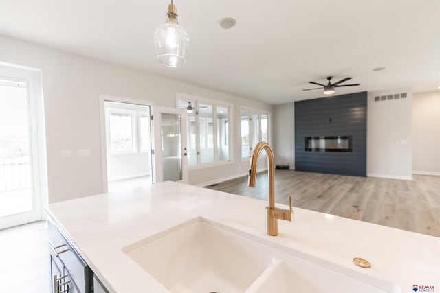 kitchen featuring light countertops, a large fireplace, ceiling fan, and visible vents