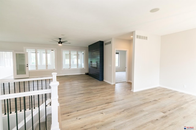 unfurnished living room featuring baseboards, a ceiling fan, light wood-style flooring, and visible vents