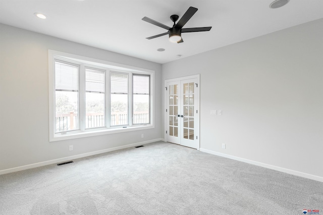 carpeted empty room featuring ceiling fan, baseboards, visible vents, and french doors